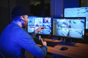 Security operator controls CCTV cameras in office at night. Modern security system and social safety concept photo