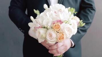 Groom holding wedding bouquet close up. . The groom with a bouquet of wedding flowers stands. Groom holding a bouquet video