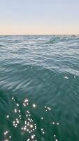 Sea water surface. Low angle view from kayak, camera flies over clear sea water. Nobody. Holiday recreation concept. Abstract nautical summer ocean nature. Slow motion. Close up. Vertical video