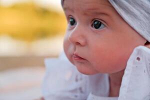 recién nacido bebé niña mentiras en el playa. en un blanco vestido. foto