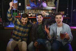 Group of excited friends in beer pub watching sports match photo