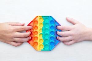 Childrens hands playing with sensory pop it toy. Sensory toy develops fine motor skills,antistress photo