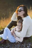 joven madre y su pequeño hija al aire libre en soleado otoño día foto