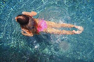 Little girl swimming in the outdoor pool photo