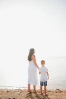 madre y hijo caminando en puesta de sol playa foto