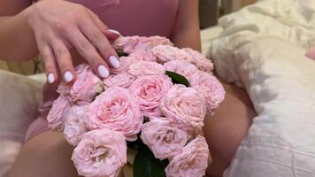 Bouquet of roses Manicure white nails stroking flowers, stroking, looking at them. girl in lingerie in a nightgown sits on the bed with a bouquet of roses video