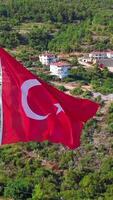 Aerial view of a Turkey national red flag. Clip. Summer green mountain and vegetation with buildings. video