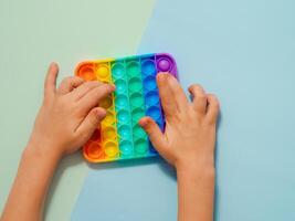 Kid hands play with popit toy over blue background photo