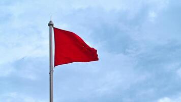 Vietnamese flag on flagpole flutters in wind against a cloudy sky. Slow motion video