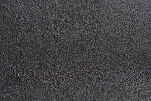 Detailed close-up of a rough black sandpaper texture, ideal for backgrounds, construction, or industrial themes. photo