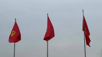 Three red flags featuring yellow symbols flutter against a gray sky, representing Vietnam and communism video