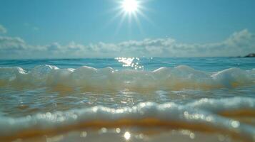 Waves roll softly against the sand, sparkling under the bright midday sun photo