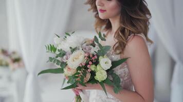 Attractive bride in fancy white wedding dress with stylish bunch of flowers. Wedding day of bride in bridal gown. Beauty woman and bouquet. Portrait of a model in a beautiful bridal dress. video