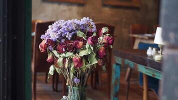 Dried Roses and Beautiful Purple Flowers Set Against a Charming Rustic Cafe Background video