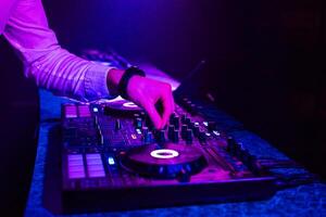 DJ plays music with his hands on a mixer controller photo