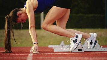 Female Runner on Athletics sprint race starting blocks on a dark background video