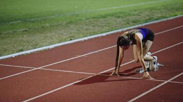 Strong Young Man Starting a Race From Track Starting Blocks Position on a Dark Stadium in the Evening. Cinematic Portrait of a Fit Male Sprint Runner Participating in a Competition video