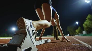 Female Runner on Athletics sprint race starting blocks on a dark background video