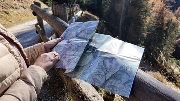 uma caucasiano mulher segurando uma mapa explora uma floresta trilha durante outono, simbolizando aventura e exploração video