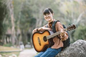 happy asian teen playing guitar music entertainment outdoor travel in the park photo