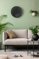 The stylish composition at living room interior with green wall, design gray sofa, coffee table, dark ornament and elegant personal accessories. Beige pillow. Cozy apartment. Template. photo