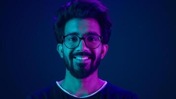 Portrait Indian man Muslim guy developer coding worker smile computer internet technology hacker Arabian male in glasses smiling neon blue ultraviolet studio background high-tech future cyberspace photo