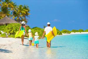 família caminhando com flutuadores em uma praia foto