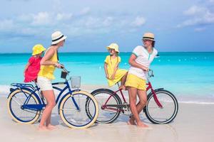 família se divertindo andando de bicicleta na praia foto