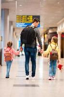 família feliz com dois filhos no aeroporto divirta-se esperando o embarque foto