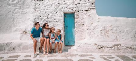 pais e filhos na rua da típica aldeia tradicional grega na ilha de mykonos, na grécia foto