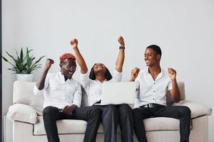 bequemes Sofa. mit Laptop. gruppe afroamerikanischer geschäftsleute, die beim zusammensitzen arbeiten foto