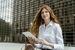 jung Geschäftsfrau im das Stadt, mit Digital Tablette foto