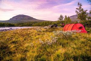 rött campingtält vid en flod foto