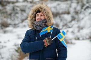 skandinavisk man med Sveriges flagga i svenska vinterlandskap. foto