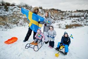 skandinavisk familj med Sveriges flagga i svenska vinterlandskap. foto