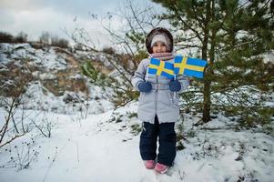 skandinavisk flicka med Sveriges flagga i svenska vinterlandskap. foto