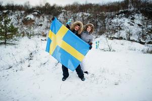 skandinaviska par med Sveriges flagga i svenska vinterlandskap. foto