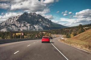 bilresa med bilkörning på vägen med klippiga berg i höstskogen vid banff nationalpark foto