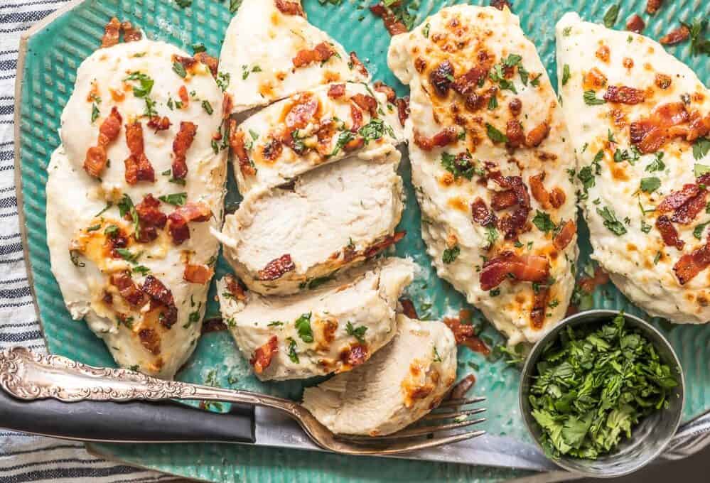 Chicken breasts with bacon and ranch dressing on a blue plate.