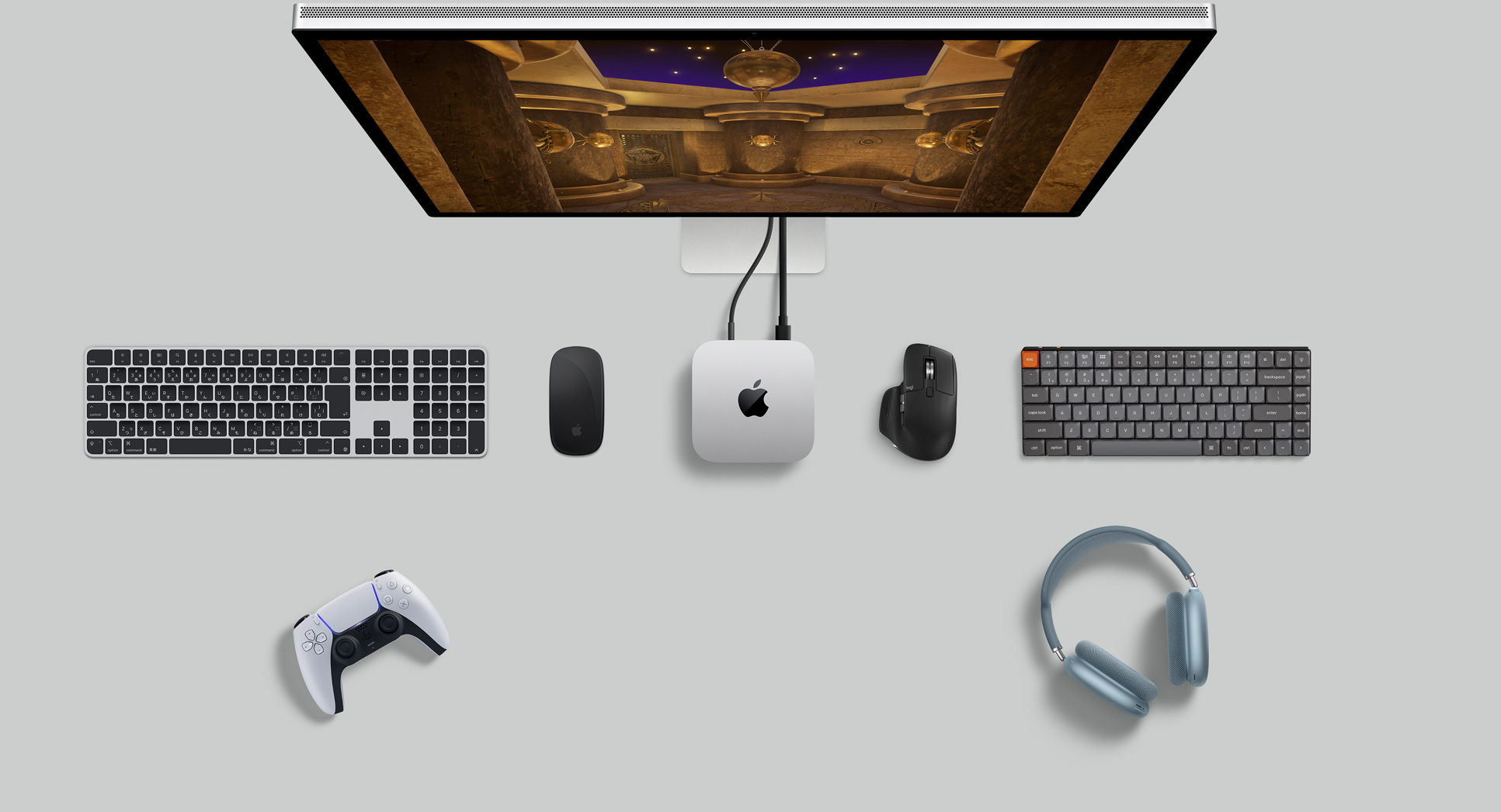 デスク上に置かれたシルバーのMac miniを上から見た図。ディスプレイ、ワイヤレスキーボード、ワイヤレスマウス、ゲームコントローラ、AirPods Maxが一緒に配置されている