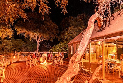 Personen an einem Lagerfeuer auf dem Holzdeck in Botswana