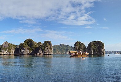 Holzschiff vor den Felsen der Halong Bucht in Vietnam