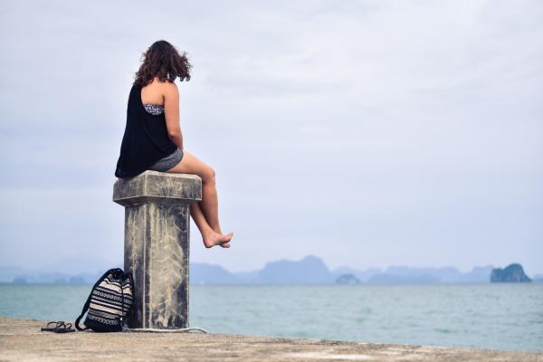 Woman in Black Shirt Sitting Near Body of Water during Daytime