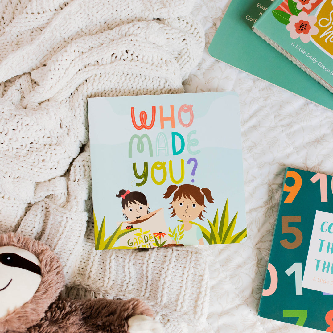 Who Made You? Children's Board Book sitting on blanket