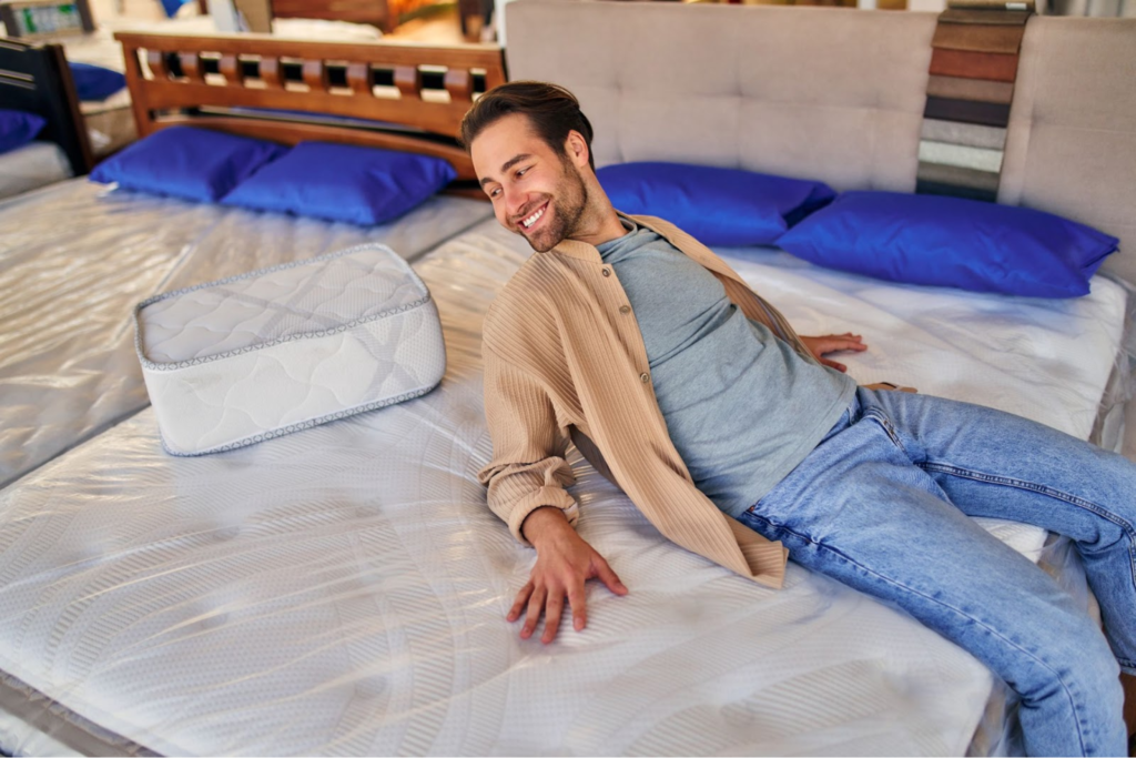 A man testing mattresses and pillows at a mattress store.