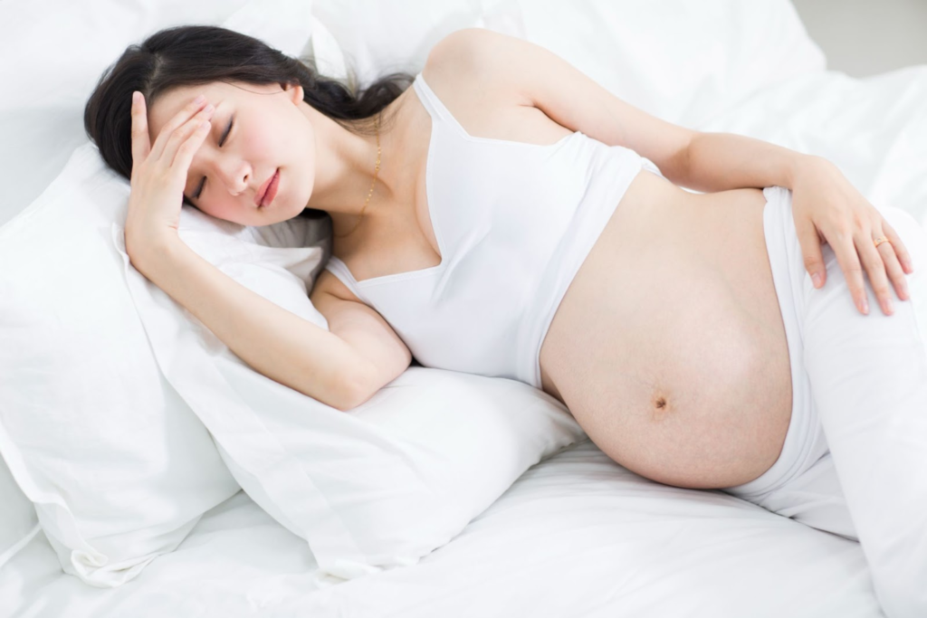 A pregnant woman sleeping on her side in bed.