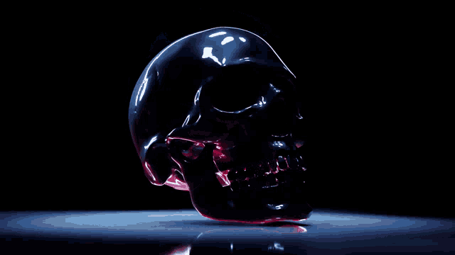 a black skull is floating in the air on a dark surface