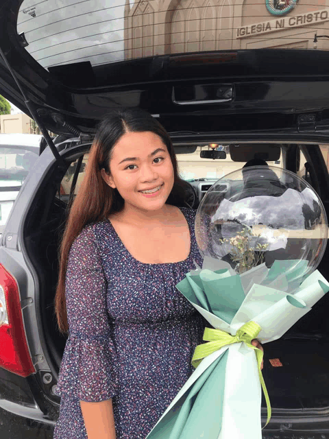 a woman holds a bouquet of flowers in front of an iglesia ni cristo sign