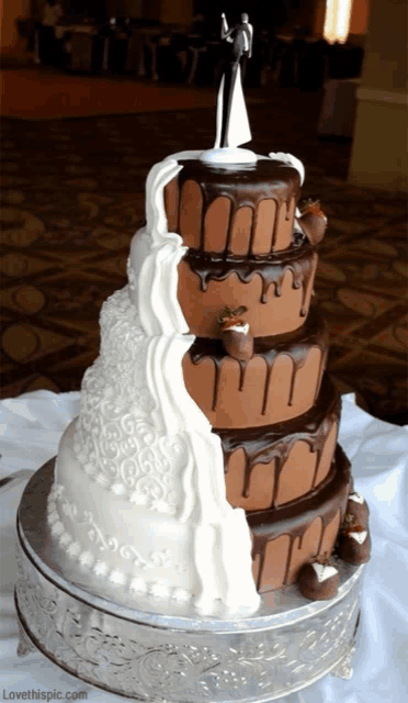 a white and chocolate wedding cake with a bride and groom topper