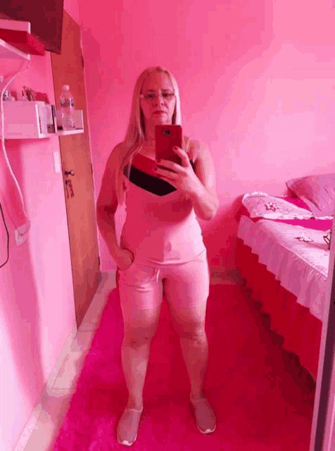 a woman taking a selfie in a pink room